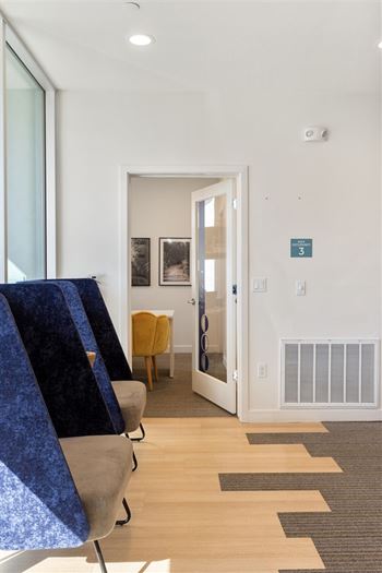 A room with a blue chair and a brown rug.